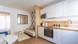 A compact kitchen with white cabinets, a wooden countertop, and a built-in oven.