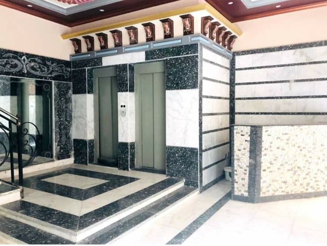 A lobby with a marble floor, a staircase, and a door leading to another room.