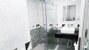 Une salle de bain moderne avec une douche en verre, un lavabo blanc et un sol carrel é en marbre.