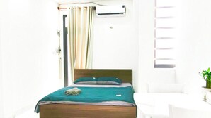 Une chambre à coucher lumineuse et moderne, avec un lit, une petite table et une chaise.