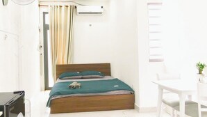 Une chambre d’hôtel équipée d’un lit, d’un bureau, d’une chaise, d’un climatiseur et d’un ventilateur de plafond.