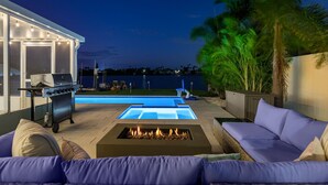 A backyard with a pool, a grill, and a fire pit. - Waterfront • Walk to Beach • Pool • Kayaks • Bikes (Indian Rocks Beach)