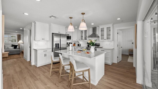 A modern kitchen with white cabinetry, a central island with bar stools, stainless steel appliances, and pendant lighting. - Waterfront • Walk to Beach • Pool • Kayaks • Bikes (Indian Rocks Beach)