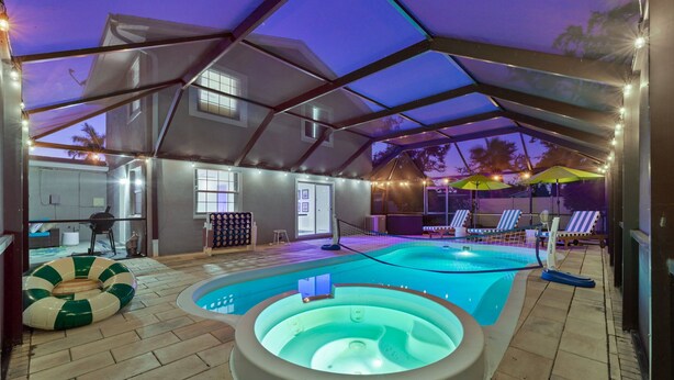 Et indendørs poolområde med jacuzzi, liggestole og en overdækket terrasse.
