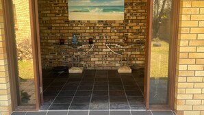 A room with a brick wall, a framed picture of a beach, and a meditation area with a statue and a small altar. - Exclusive Sunrise Room (Surfers Paradise)