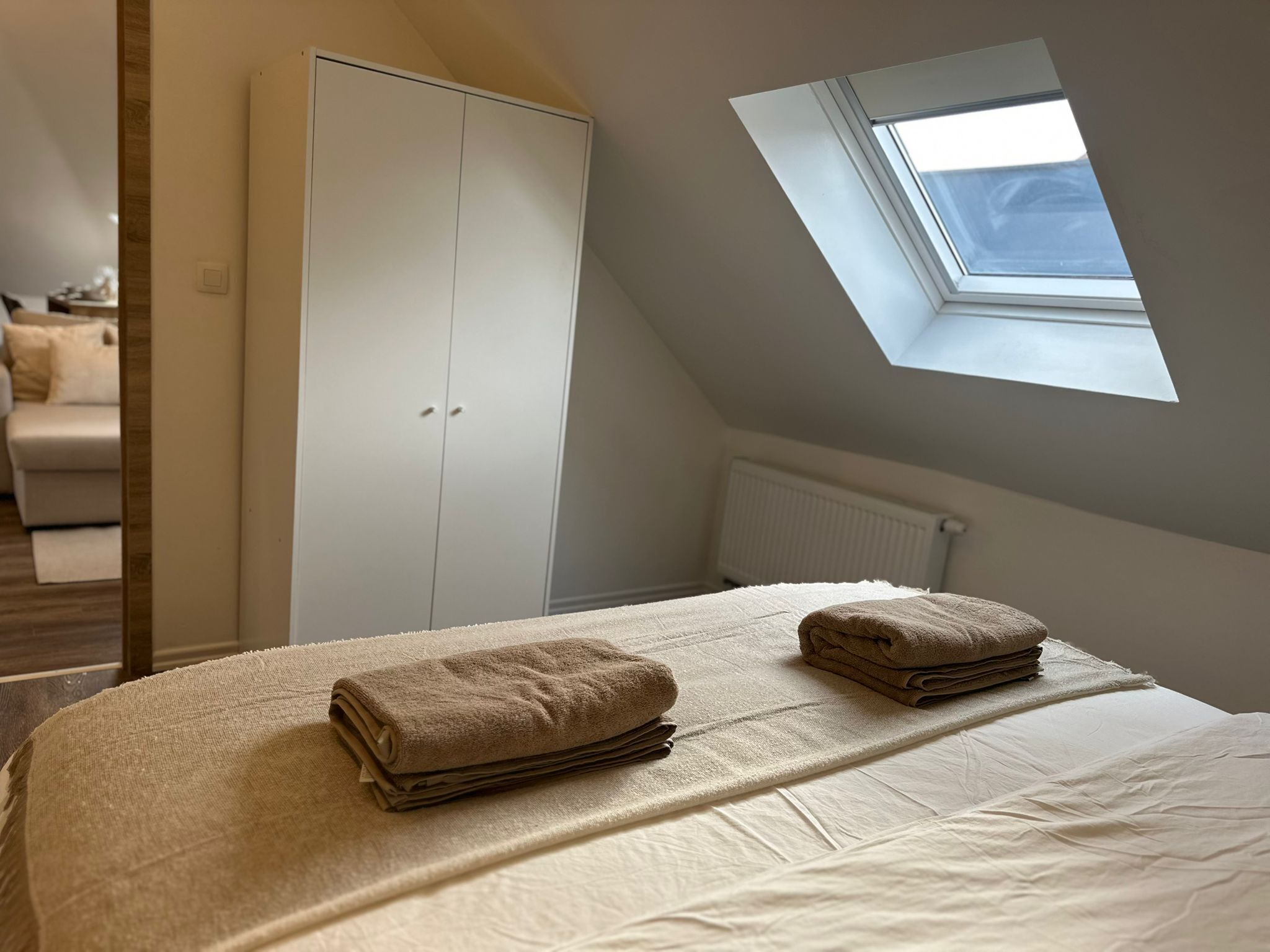 Un dormitorio con tragaluz, un armario y una cama con toallas dobladas.