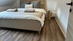 A bedroom with a bed, pillows, a bedside table with a lamp, and a wooden floor. - Cozy 1BR plus LR Apt Ghent Gravensteen (Ghent)
