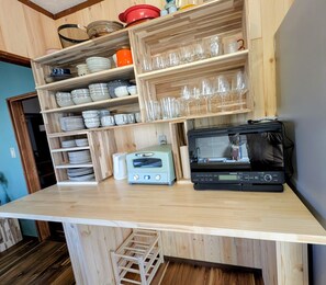 A kitchen with wooden shelves holding dishes and glasses, a toaster, and a black radio.