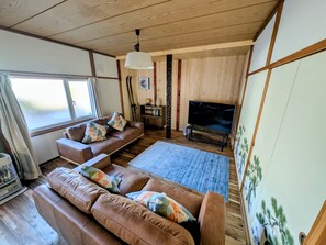 A living room with a sofa set, a television, and a large window.