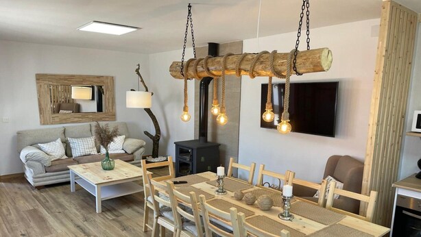 Ein modernes Wohnzimmer mit einem Holzespeisetisch, einer Couch und einem an der Wand befestigten Fernseher.