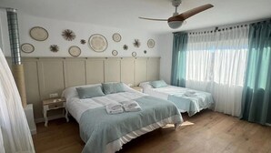 Ein Hotelzimmer mit zwei Betten, einem Deckenventilator, dekorativen Wandplatten und einem Fenster mit Vorhängen.