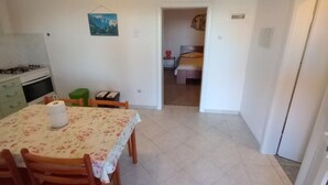 A compact room with a dining table, chairs, a bed, and a small kitchenette. - Comfort One Bedroom Apartment with Terrace and Sea view (Sveta Nedjelja)