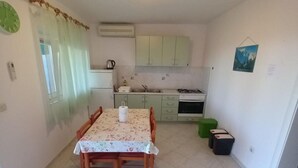 A compact kitchen with a dining table, cabinets, and a small stove. - Comfort One Bedroom Apartment with Terrace and Sea view (Sveta Nedjelja)