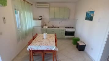 A compact kitchen with a dining table, cabinets, and a small stove.