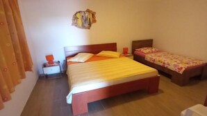 A bedroom with a large bed, a smaller bed, a nightstand, and a wall-mounted decoration. - Comfort One Bedroom Apartment with Terrace and Sea view (Sveta Nedjelja)