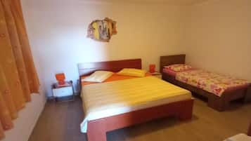 A bedroom with a large bed, a smaller bed, a nightstand, and a wall-mounted decoration.