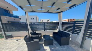 An outdoor patio area with wicker furniture, a pergola, and a view of surrounding buildings. - Elegant Villa Ilma with Pool - Villa With Pool (Vodice)