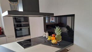 A modern kitchen with a built-in oven, a stovetop, and a fruit bowl on the counter. - Elegant Villa Ilma with Pool - Villa With Pool (Vodice)
