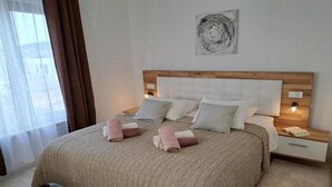 A neatly made bed with a beige quilt, two pillows, and two rolled towels. There is a wooden headboard, a wall art piece, and a nightstand with a lamp. - Elegant Villa Ilma with Pool - Villa With Pool (Vodice)