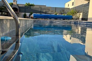 A swimming pool with a clear blue water surface, a blue pool cover, and a metal ladder. - Elegant Villa Ilma with Pool - Villa With Pool (Vodice)