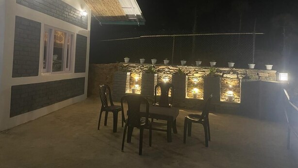 Een terras buiten, met een stenen muur, zitplaatsen en een bar met verlichting.