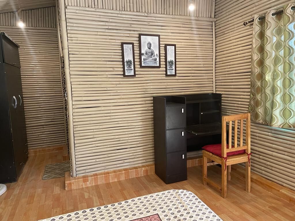 A room with a wooden floor, a desk with drawers, a chair, and a bed.