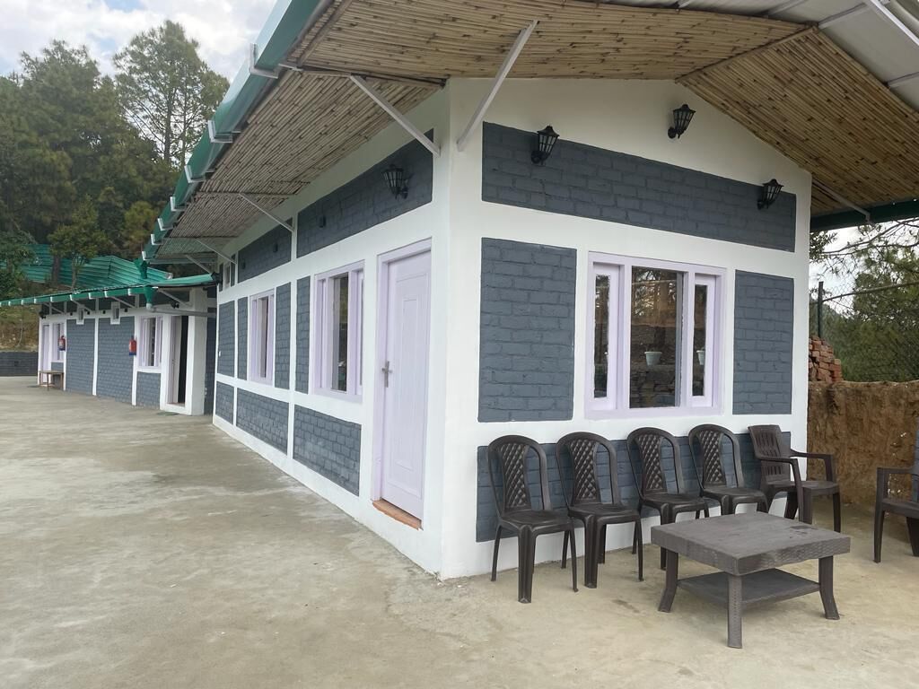 Ein Gebäude mit überdachter Terrasse, zahlreichen Fenstern und Außenmöbeln.