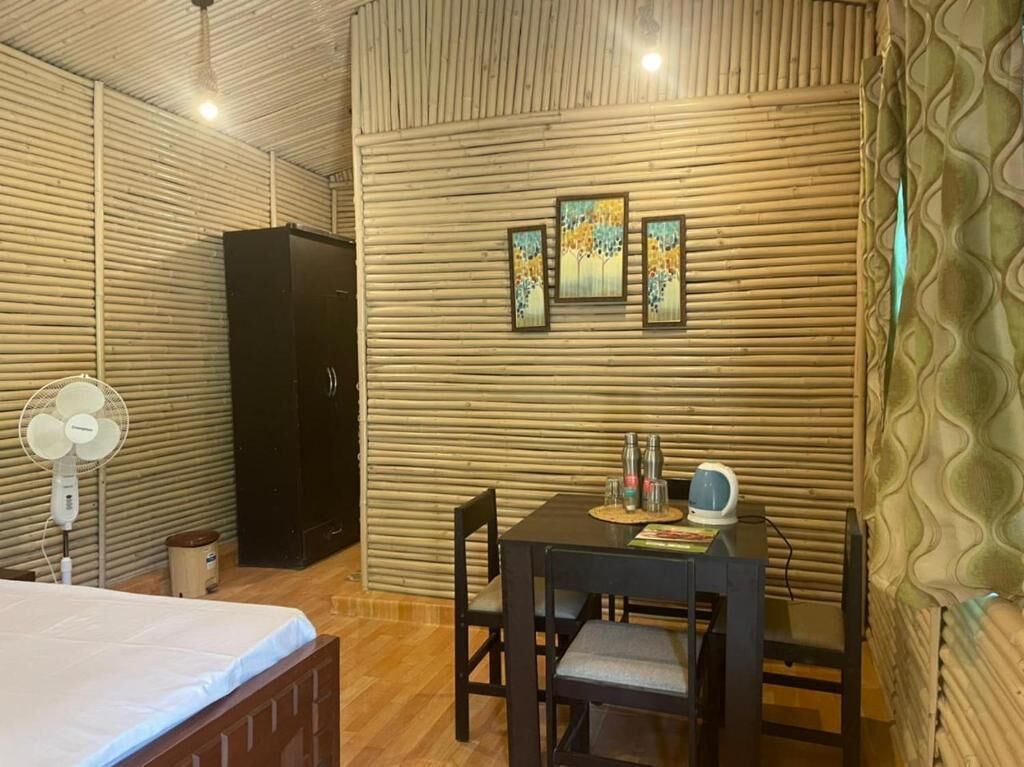 Una habitación con cama, una mesa y sillas, un ventilador y obras de arte en la pared.