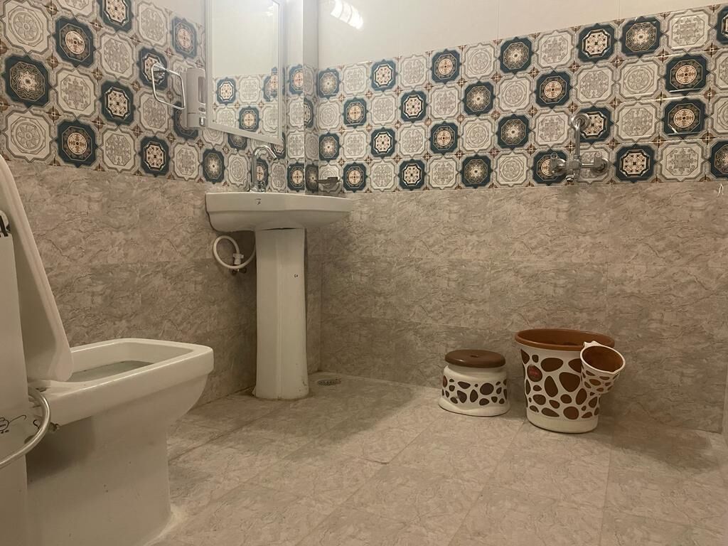 Een badkamer met toilet, wastafel en decoratieve potten.