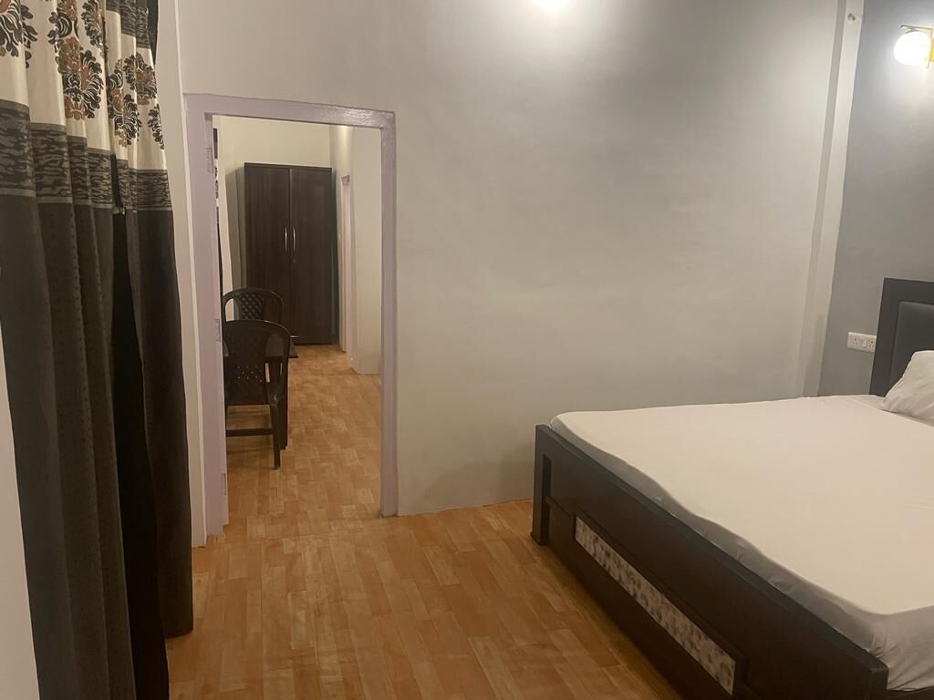 A bedroom with a bed, wooden flooring, a chair, and a wardrobe.