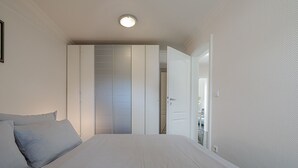 A bedroom with a bed, a wardrobe, and a door leading to another room. - Sand - Lust auf Sylt - Sand vacation apartment for 2 people (Sylt-Ost)