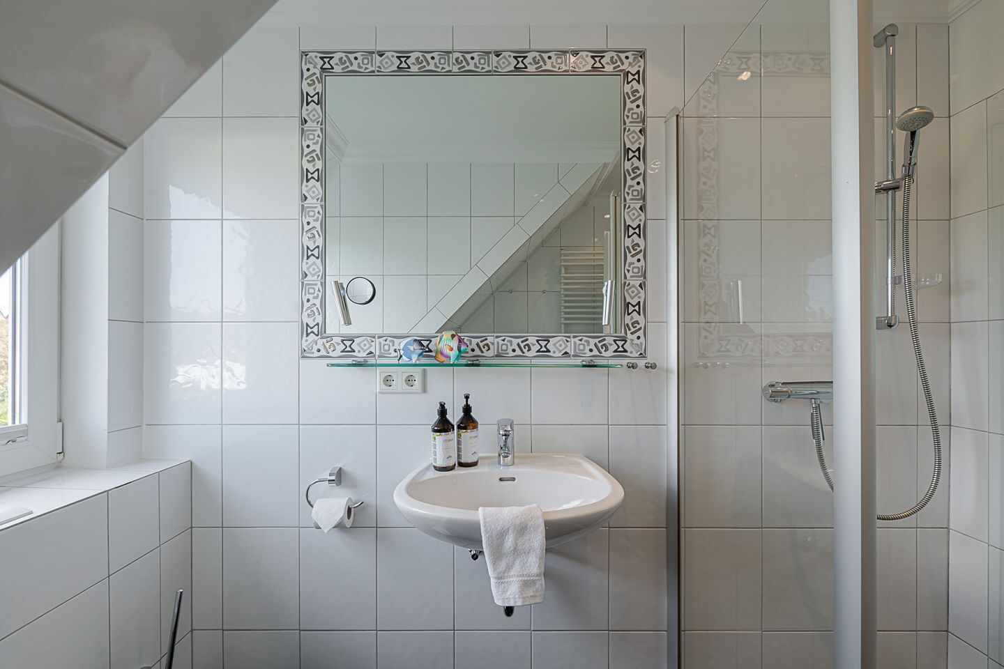 A bathroom with a white sink, a mirror with a decorative frame, and a shower area.