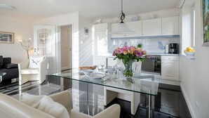 A modern kitchen with white cabinets, a glass dining table, and a vase of flowers. - Sand - Lust auf Sylt - Sand vacation apartment for 2 people (Sylt-Ost)