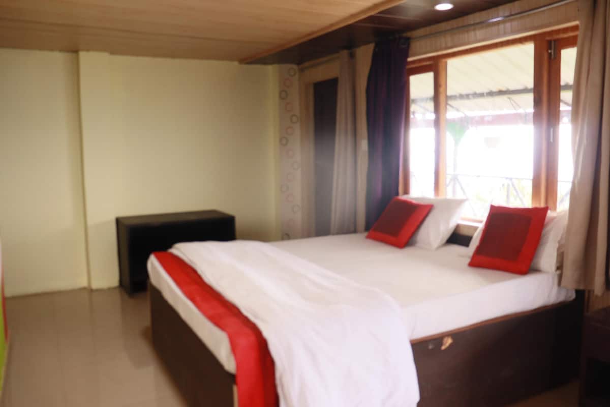 Ein Schlafzimmer mit einem großen Bett, einem Nachttisch und einem Fenster mit Vorhängen.