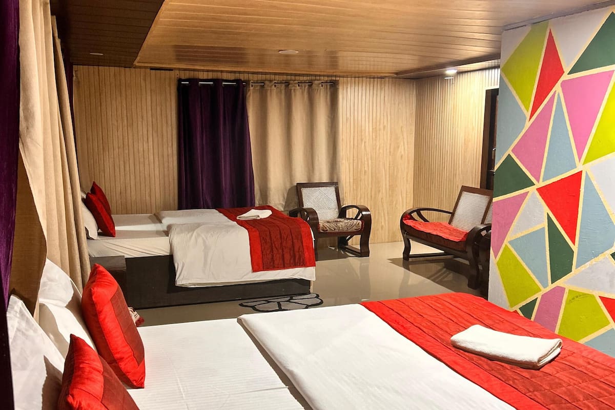 Ein Hotelzimmer mit zwei Betten, einem Sessel und einem farbenfrohen, geometrischen Wanddesign.