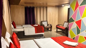 Ein Hotelzimmer mit zwei Betten, einem Sessel und einem farbenfrohen, geometrischen Wanddesign.