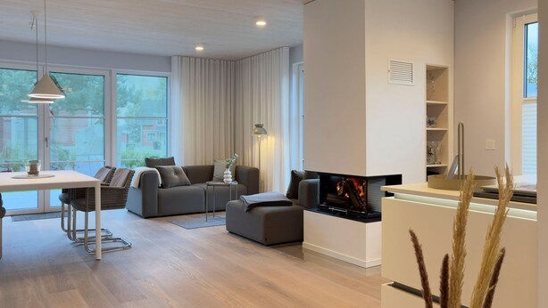 Uma sala de estar moderna com sofá, mesa de jantar e lareira.