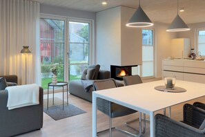 Un salon moderne avec une cheminée, un coin repas et une cuisine.
