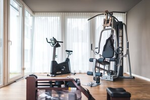 Ein Heimfitnessraum mit einem Crosstrainer, einer Hantelbank und einem Squat-Gestell.