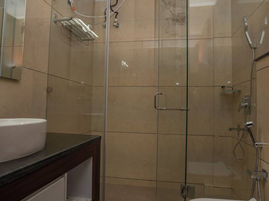 Un baño moderno con ducha de vidrio, un lavamanos blanco y un inodoro.