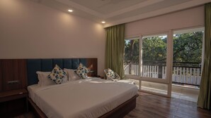 A bedroom with a large bed, wooden headboard, and a balcony with a view of trees. - Corbett Hidden Paradise (Ramnagar)