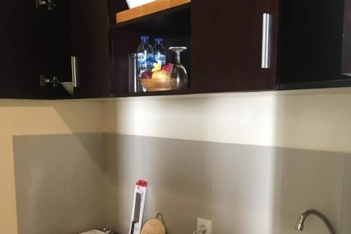 A compact kitchen with a sink, a stovetop, and a countertop with various kitchen items.