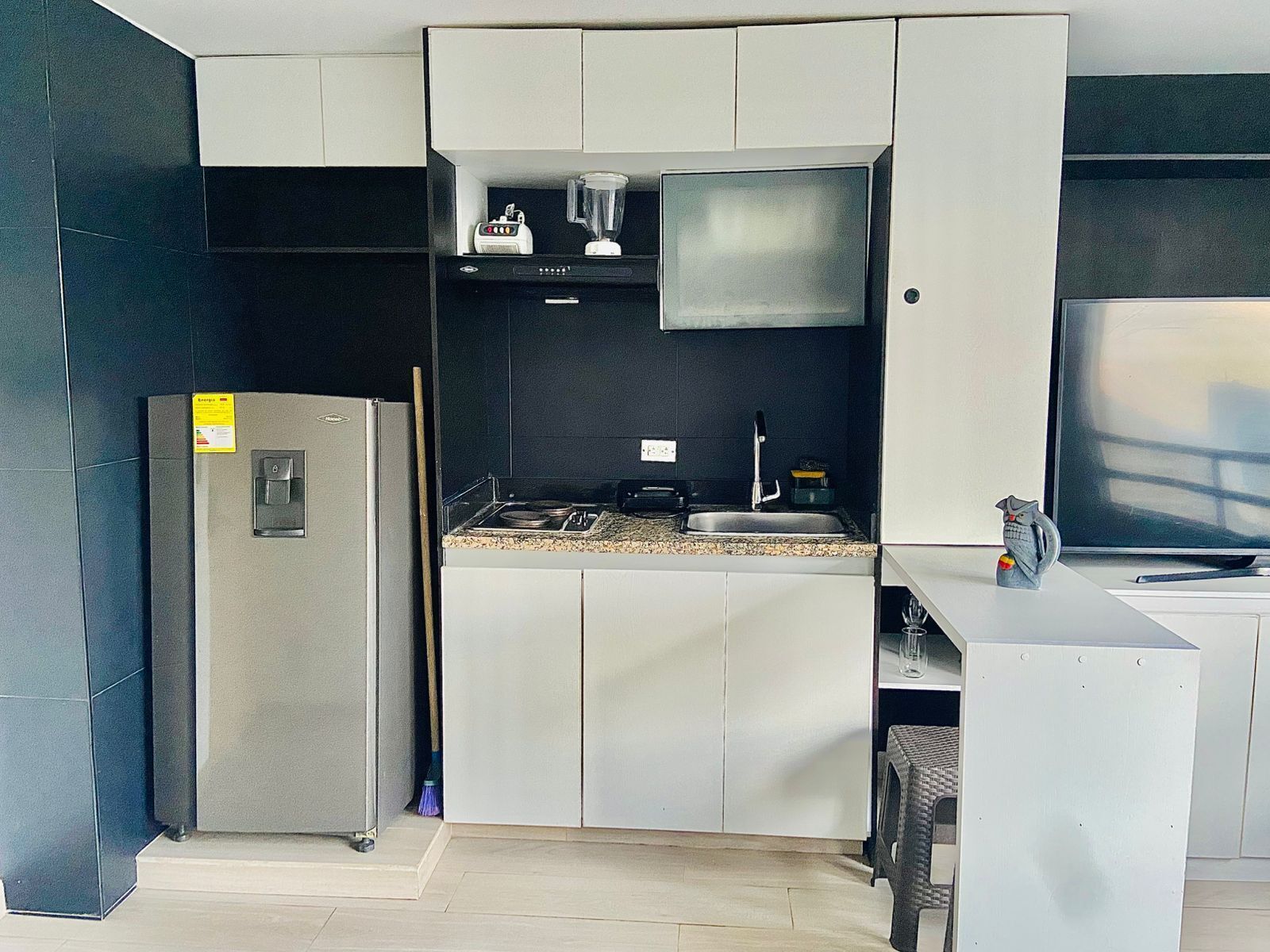 Una cocina compacta con refrigerador, lavamanos y encimera.