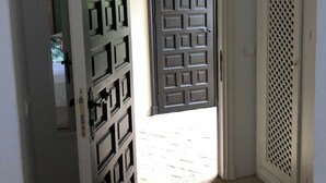 A hallway with a door leading to a room. The hallway has a tiled floor and a white wall. - PATIO ROOM SOTOGRANDE (sotogrande)