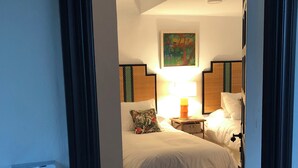 A hotel room with two beds, a painting on the wall, a bedside table with a lamp, and a wall-mounted control panel. - PATIO ROOM SOTOGRANDE (sotogrande)