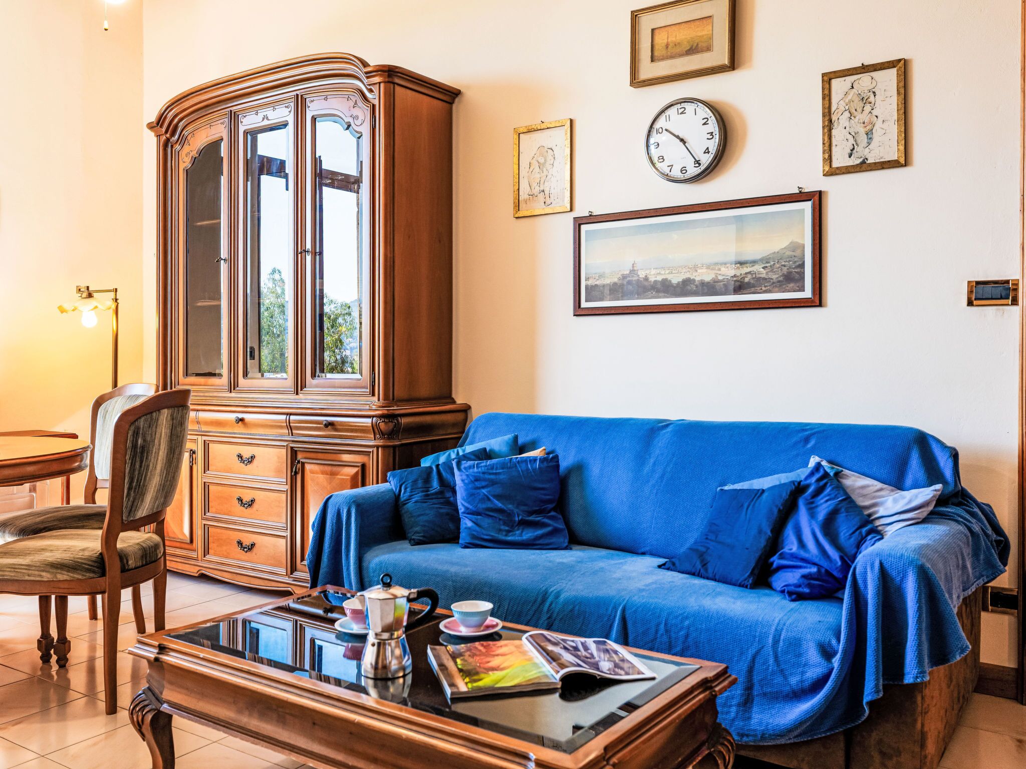 Een kamer met een blauwe bank, een houten kast en een salontafel met een tijdschrift.