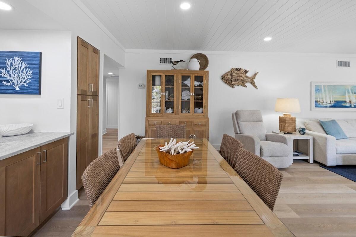 Un coin repas comprenant une table en bois, des chaises, un meuble avec des portes en verre, une décoration représentant des poissons et un tableau accroché au mur.