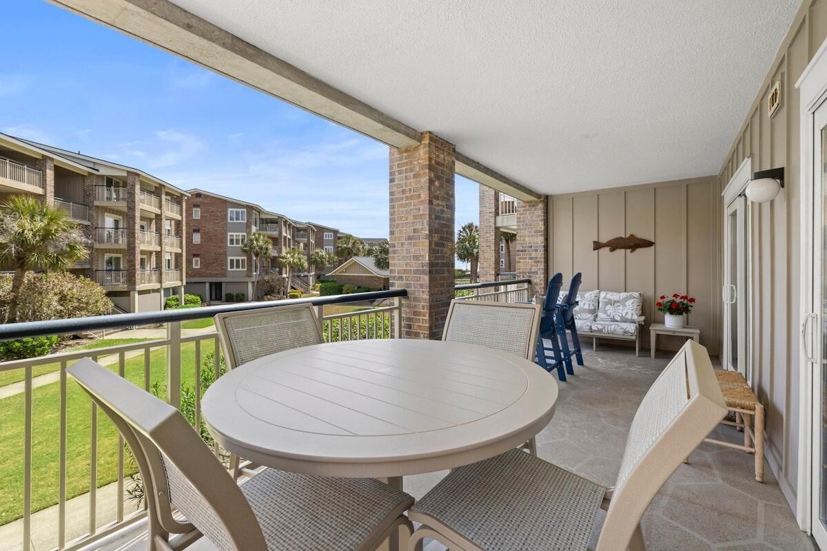 Ein Balkon mit rundem Tisch und Stühlen, einer kleinen Couch und einem Blumentopf.