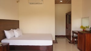 A bedroom with a wooden headboard, a bed with white bedding, a wooden desk, and a mirror. - Serene Retreat Phu Quoc (Phu Quoc)