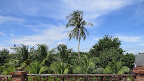A brick wall with a metal railing, palm trees, and a tiled floor. - Serene Retreat Phu Quoc (Phu Quoc)